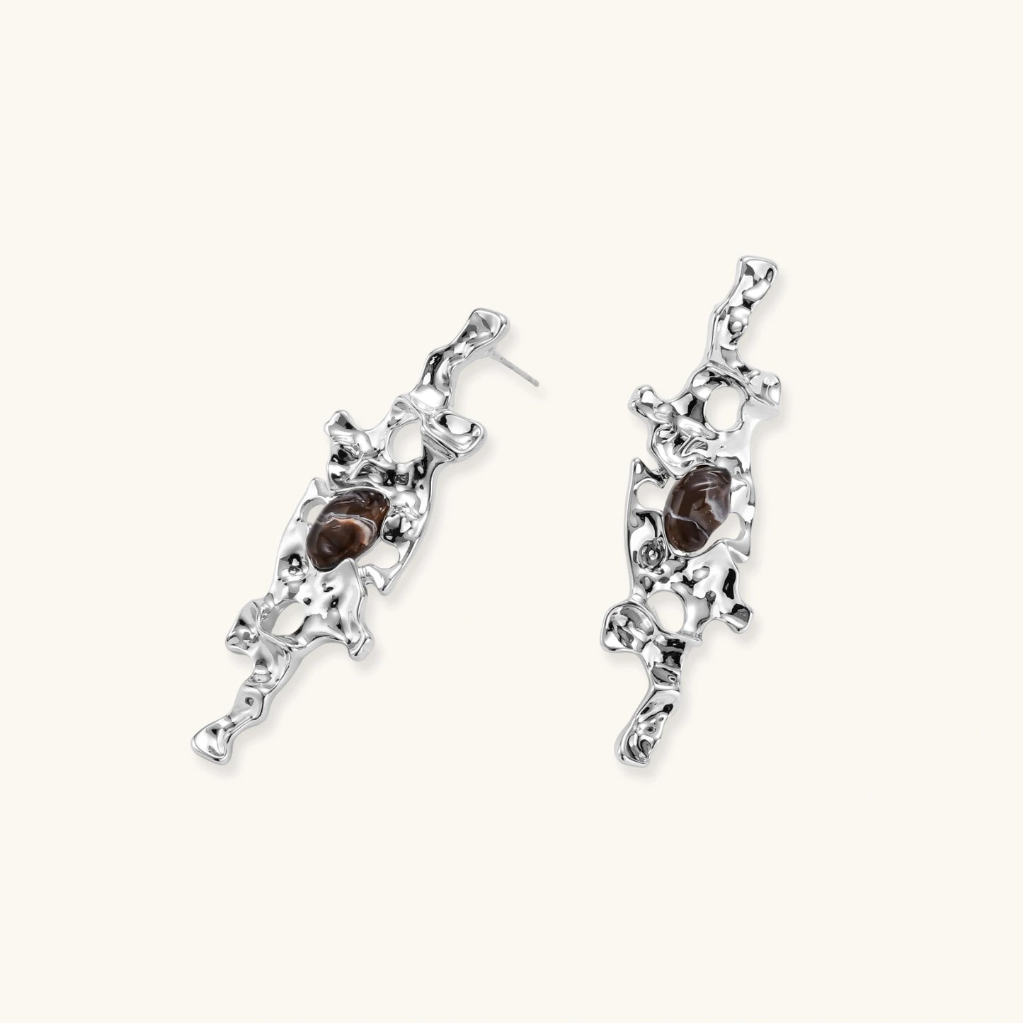 Flowing silver-toned earrings with organic liquid shapes and embedded brown resin stones on white background.