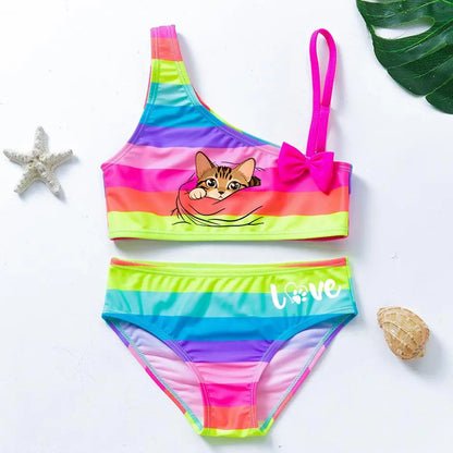 Two-piece rainbow striped girl's swimsuit featuring a golden crown 'Queen' graphic and a pink decorative bow.
