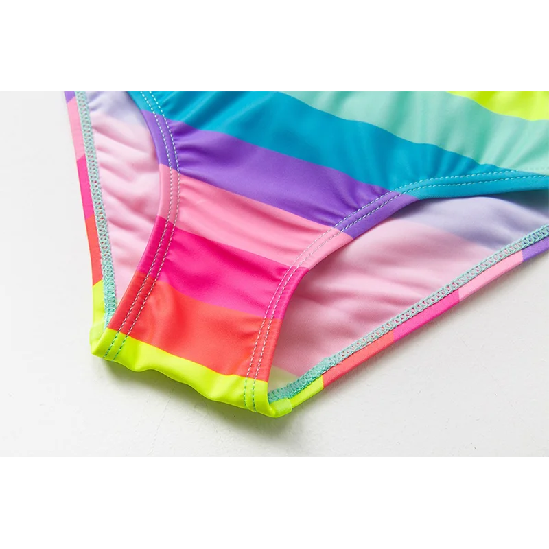 Two-piece rainbow striped girl's swimsuit featuring a golden crown 'Queen' graphic and a pink decorative bow.