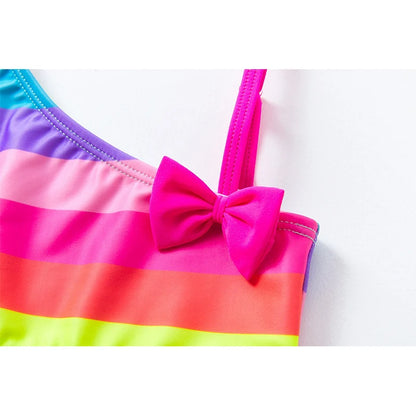 Two-piece rainbow striped girl's swimsuit featuring a golden crown 'Queen' graphic and a pink decorative bow.