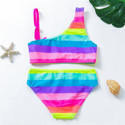 Two-piece rainbow striped girl's swimsuit featuring a golden crown 'Queen' graphic and a pink decorative bow.