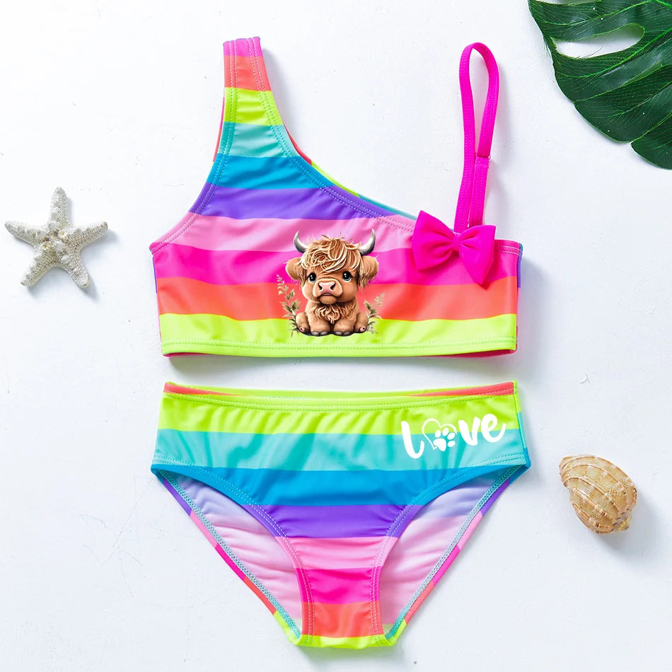 Two-piece rainbow striped girl's swimsuit featuring a golden crown 'Queen' graphic and a pink decorative bow.