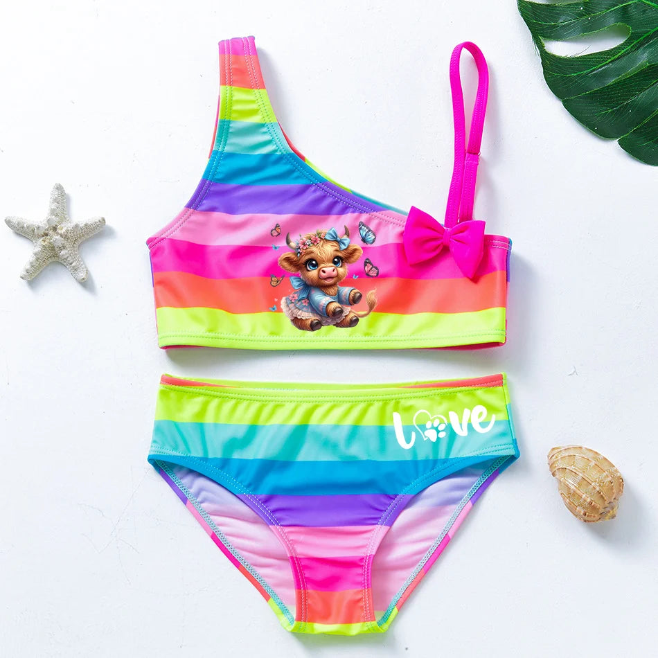 Two-piece rainbow striped girl's swimsuit featuring a golden crown 'Queen' graphic and a pink decorative bow.