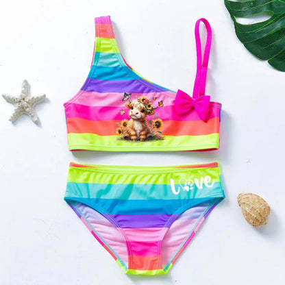 Two-piece rainbow striped girl's swimsuit featuring a golden crown 'Queen' graphic and a pink decorative bow.