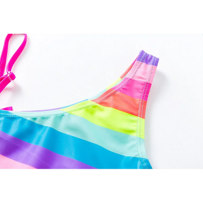 Two-piece rainbow striped girl's swimsuit featuring a golden crown 'Queen' graphic and a pink decorative bow.