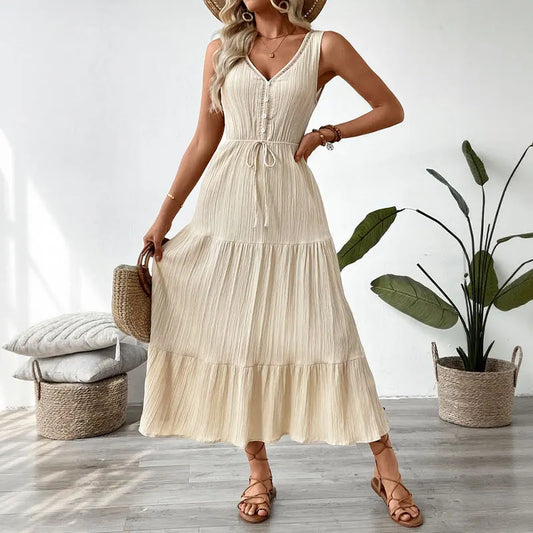 Elegant sleeveless cream sun dress with drawstring waist and button details, styled with summer accessories.