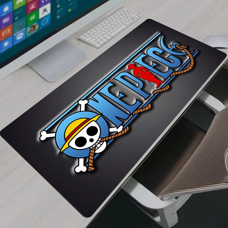 Large One Piece anime logo mouse pad on a white desk setup featuring a monitor and keyboard.