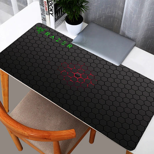 Sleek black Razer hexagon pattern XXL gaming mouse pad on a white desk with a laptop.