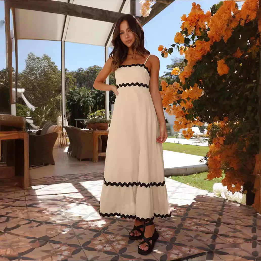 Woman wearing a white midi dress with black scalloped trim standing on a Mediterranean patio.