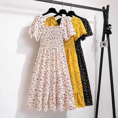 Collection of Natonyan floral chiffon dresses in white, yellow, and black hanging on a clothes rack.