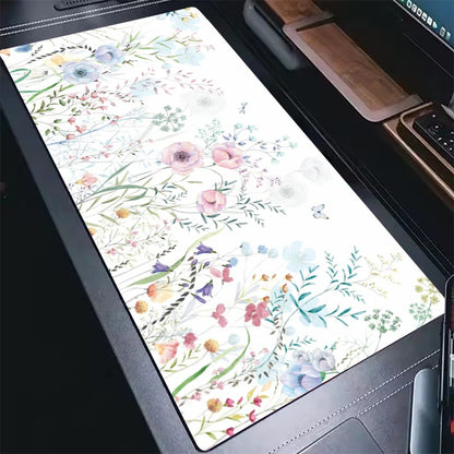 Close-up of a floral patterned desk mat with watercolor flowers on a dark desk surface.