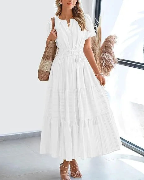 Woman wearing a white tiered boho midi dress with bubble sleeves and smocked waist standing in a bright room.